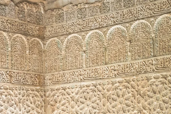 Intricate carved stucco wall with Arabic calligraphy