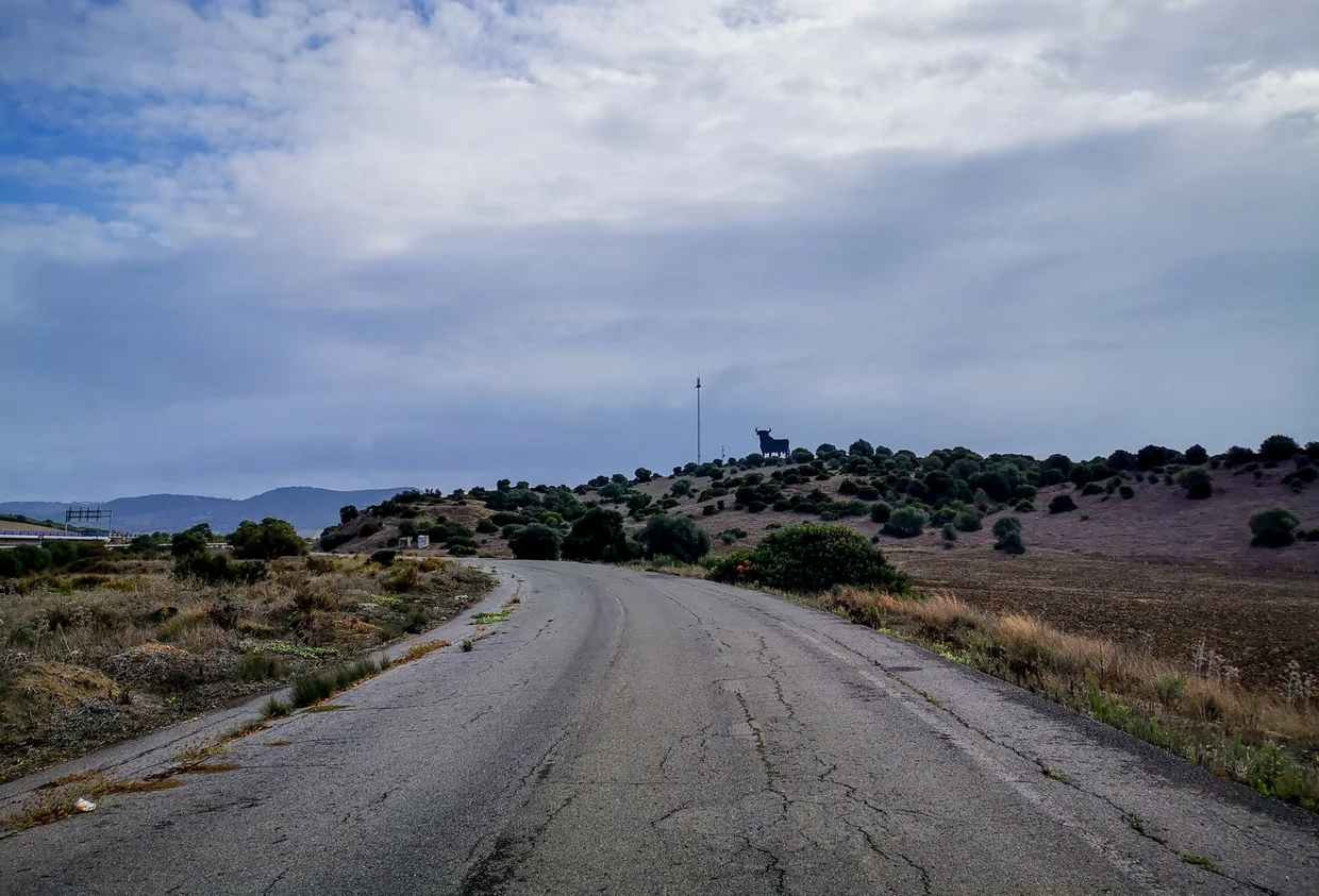 Road through the Andalusian countryside with the Osborne bull on the hilltop