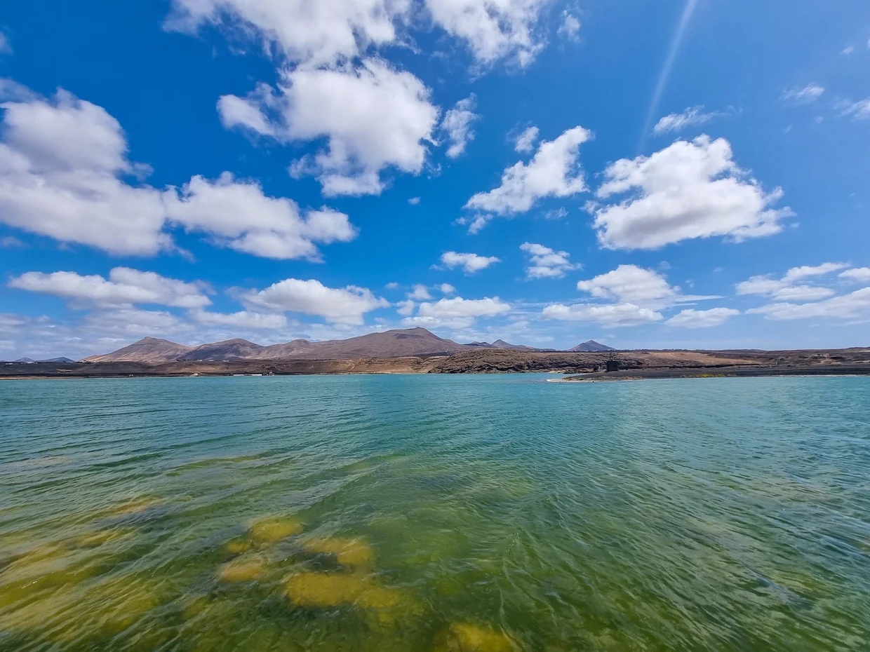 Emerald-green lagoon with volcanic mountains and turquoise ocean behind