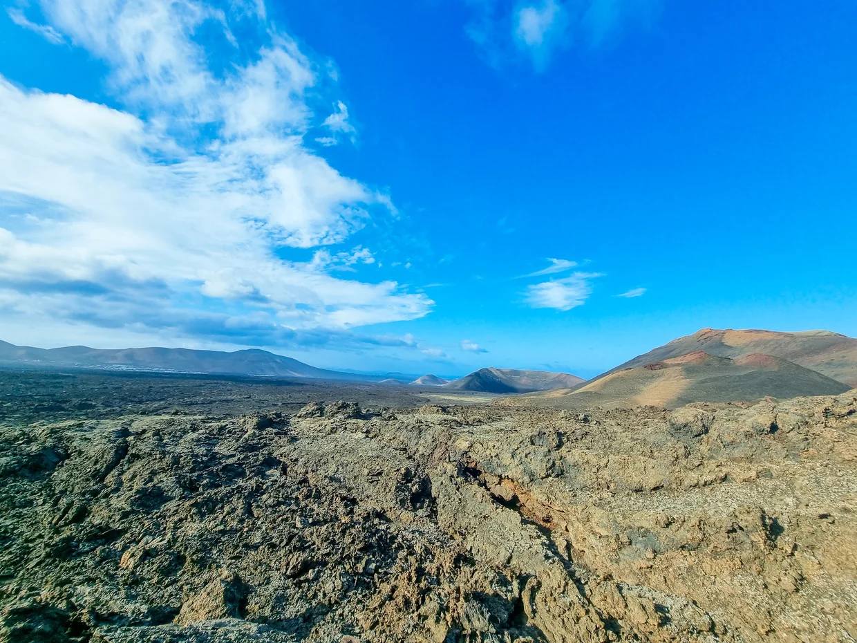 Panoramic view of Timanfaya lava fields with volcanic cones under dramatic sky