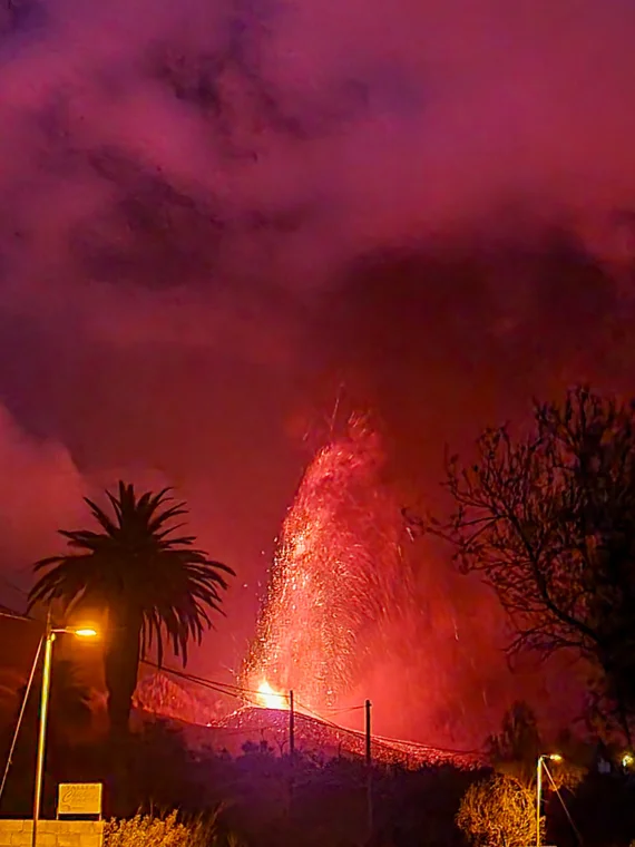 The 2021 eruption at night, lava fountain and palm tree silhouette