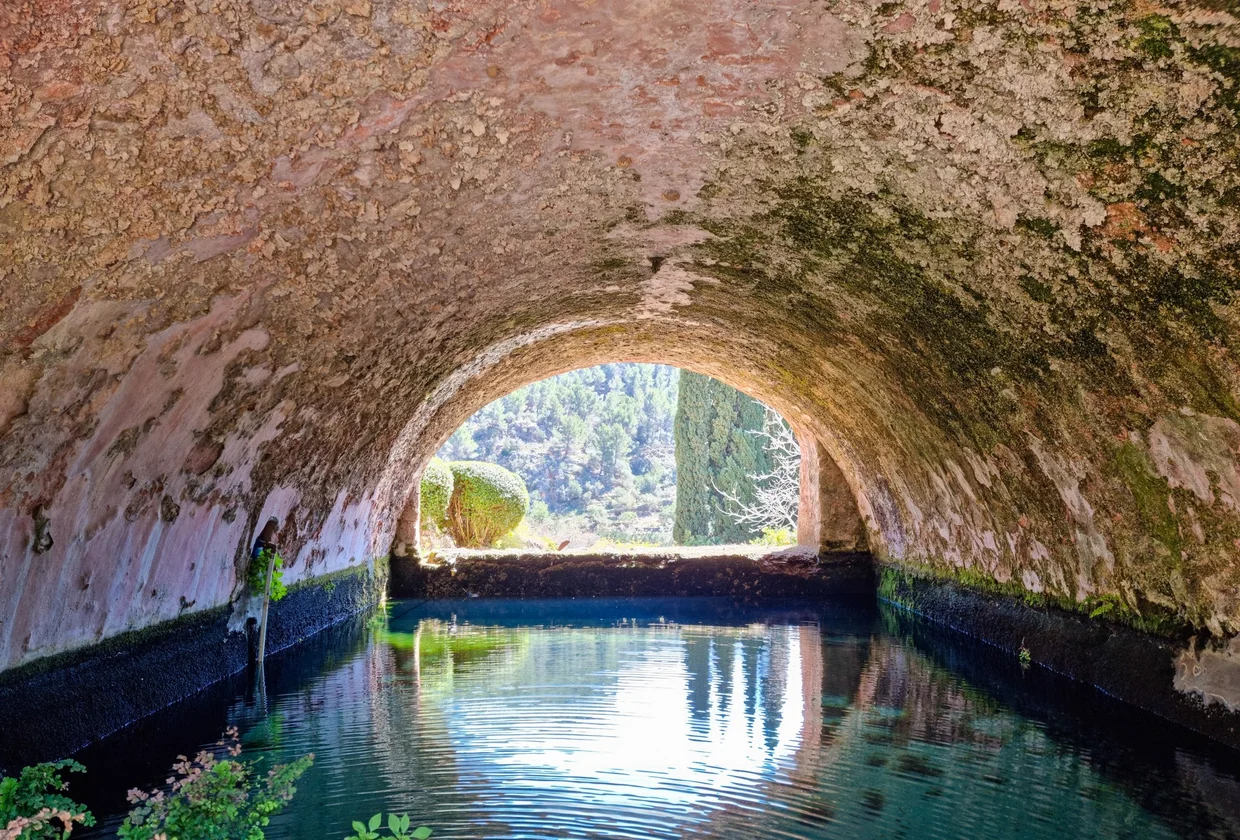 Stone arch tunnel over calm green water channel