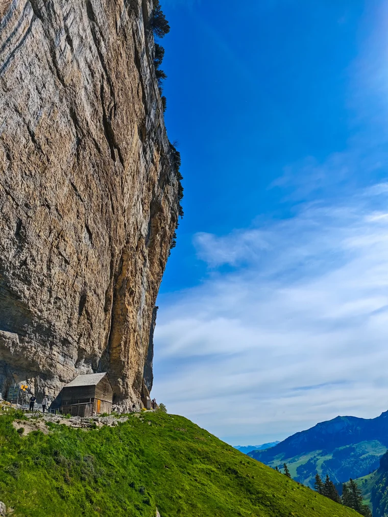 Berggasthaus Aescher seen from the side, the full sweep of cliff rising above it