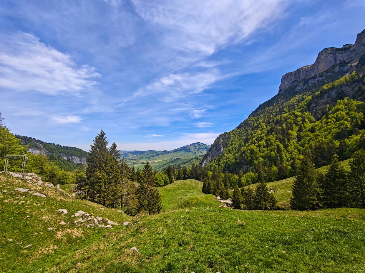 View down a winding alpine road into a wide green valley