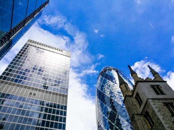 Looking up at the Gherkin and glass towers with a church steeple in between