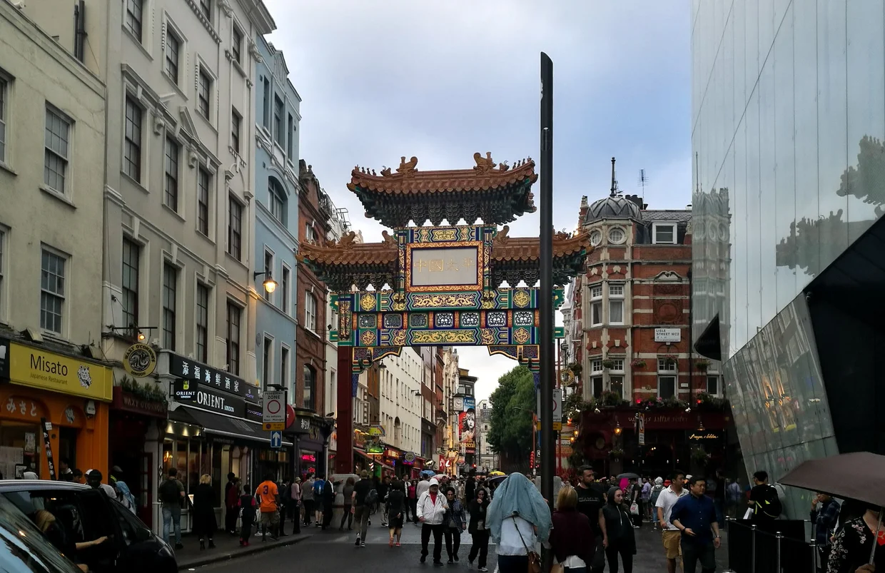 The ornate Chinatown gate spanning the street, pedestrians passing through