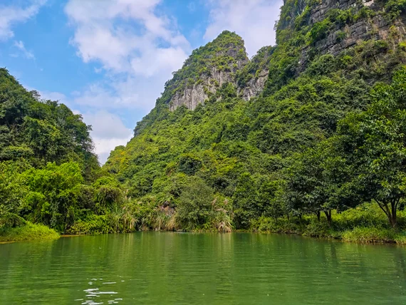 Lush valley-like bend with karst slope and bright green water in Trang An